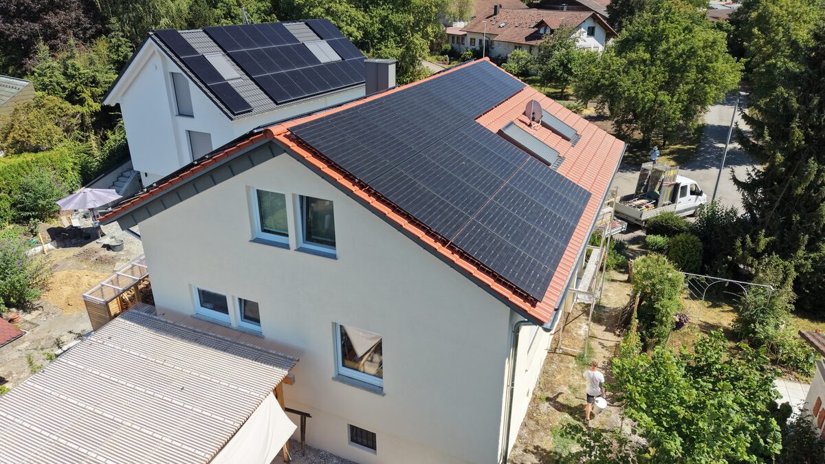 Einfamilienhaus mit rotem Ziegeldach und großflächiger Photovoltaikanlage aus der Drohnenperspektive